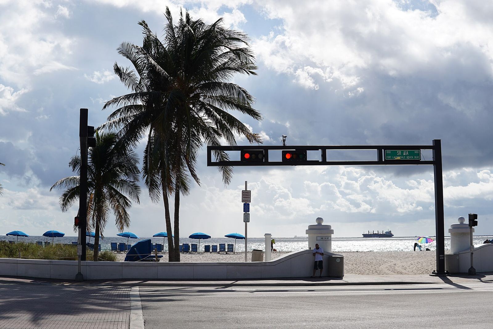 Palm trees and a traffic light along the beachfront road in Fort Lauderdale, with the ocean behind