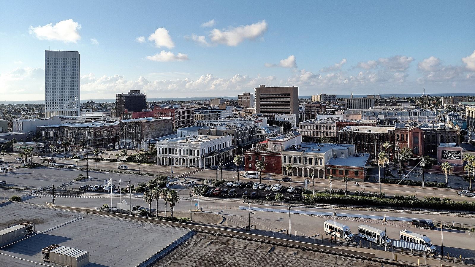 Downtown Galveston rooftops and historic buildings seen from above the harbor side, under a blue sky