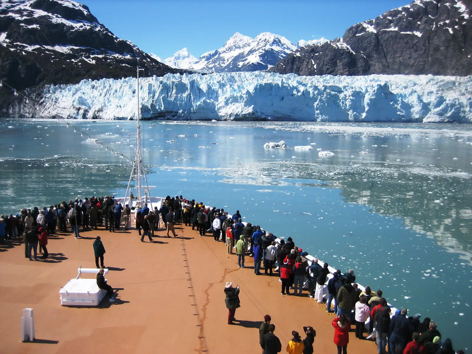 Passengers on a cruise ship bow facing a tidewater glacier in Glacier Bay National Park, Alaska