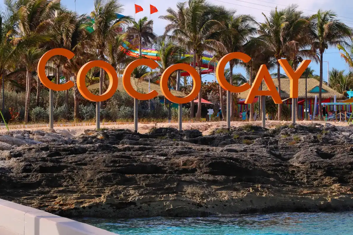 Large orange letters spelling the island's name on rocks above the sea in The Bahamas