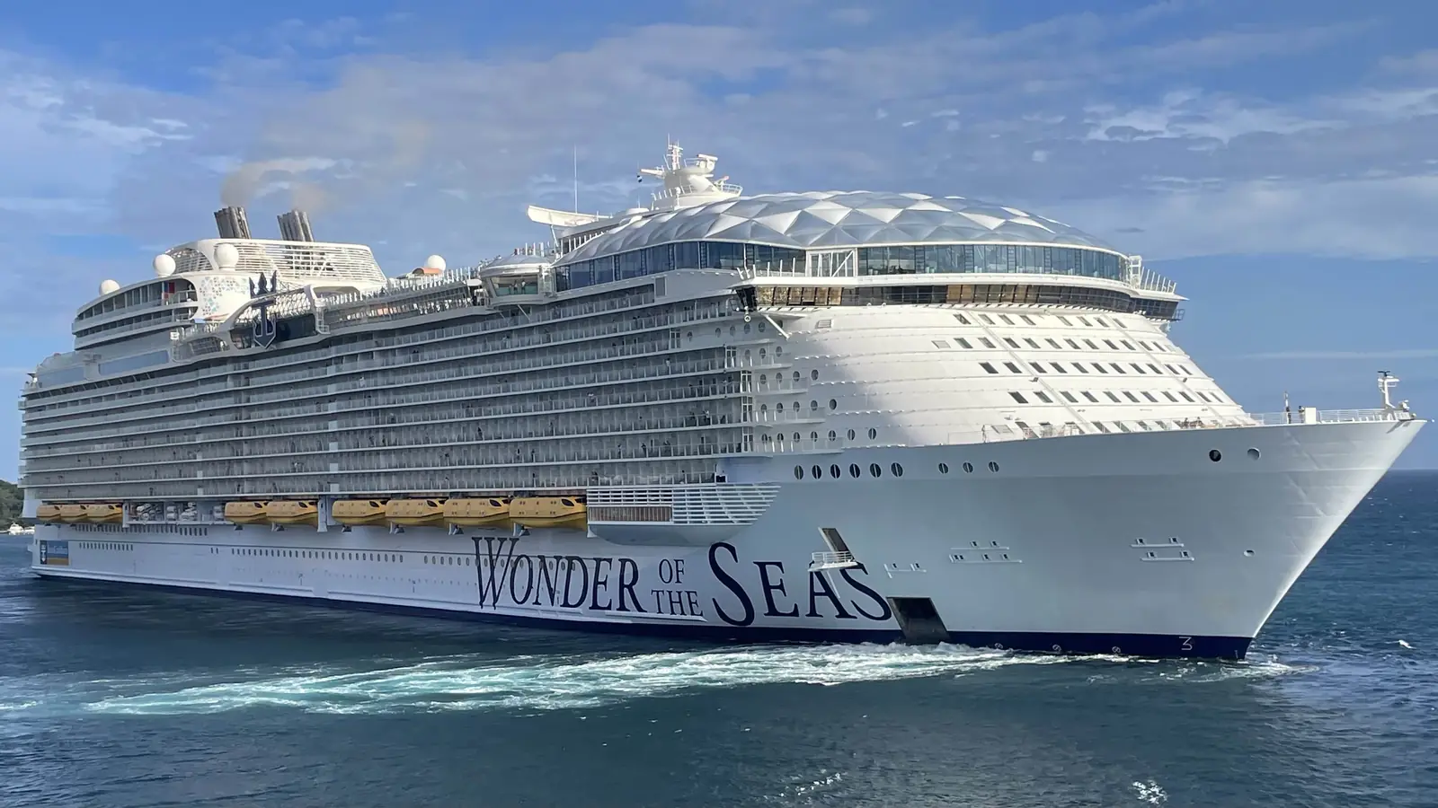 A giant white cruise ship sailing in blue water