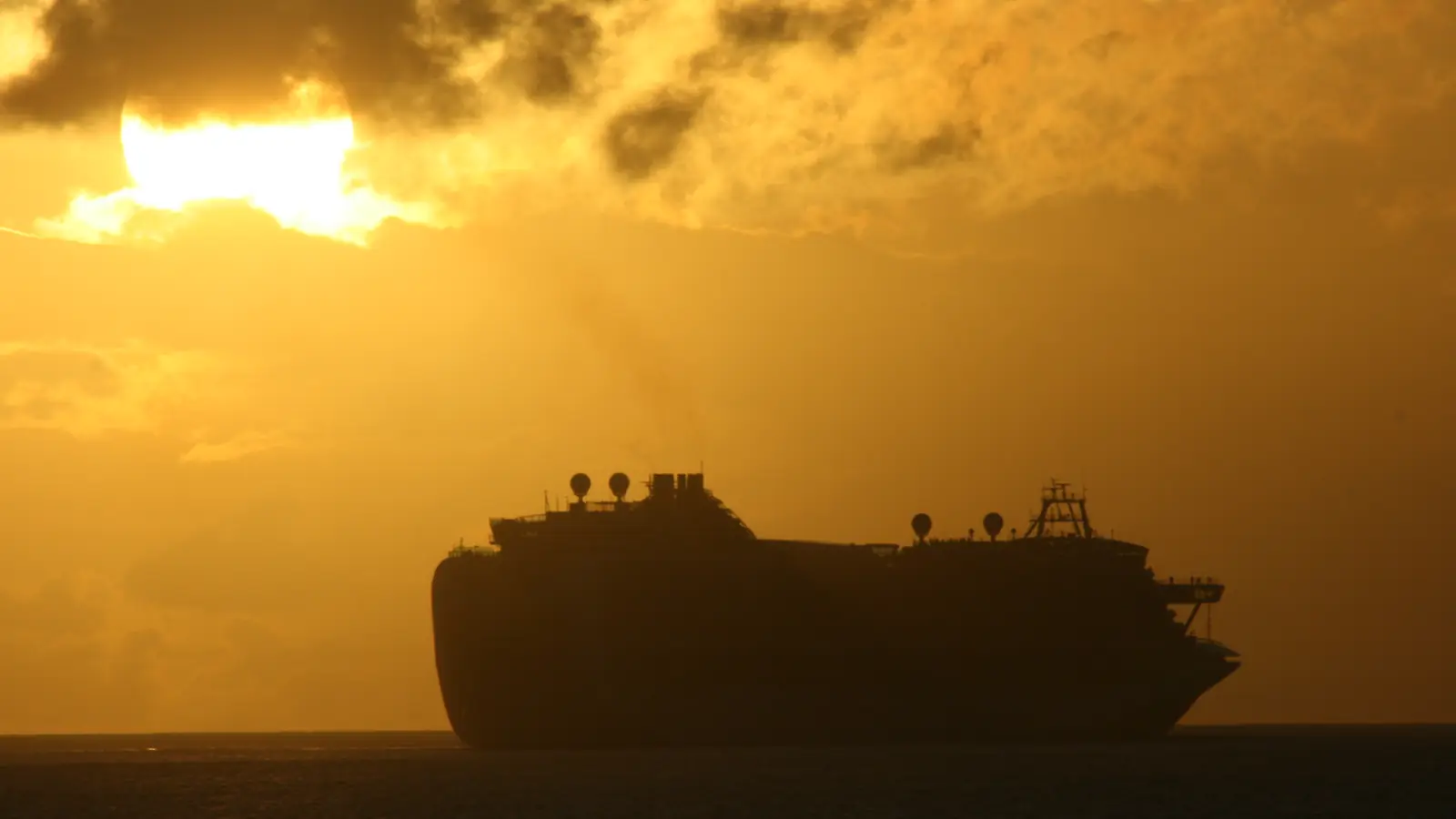 A cruise ship sailing away from port at sunset