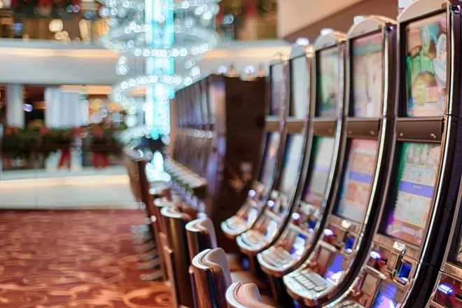 Row of slot machines and stools in a bright casino