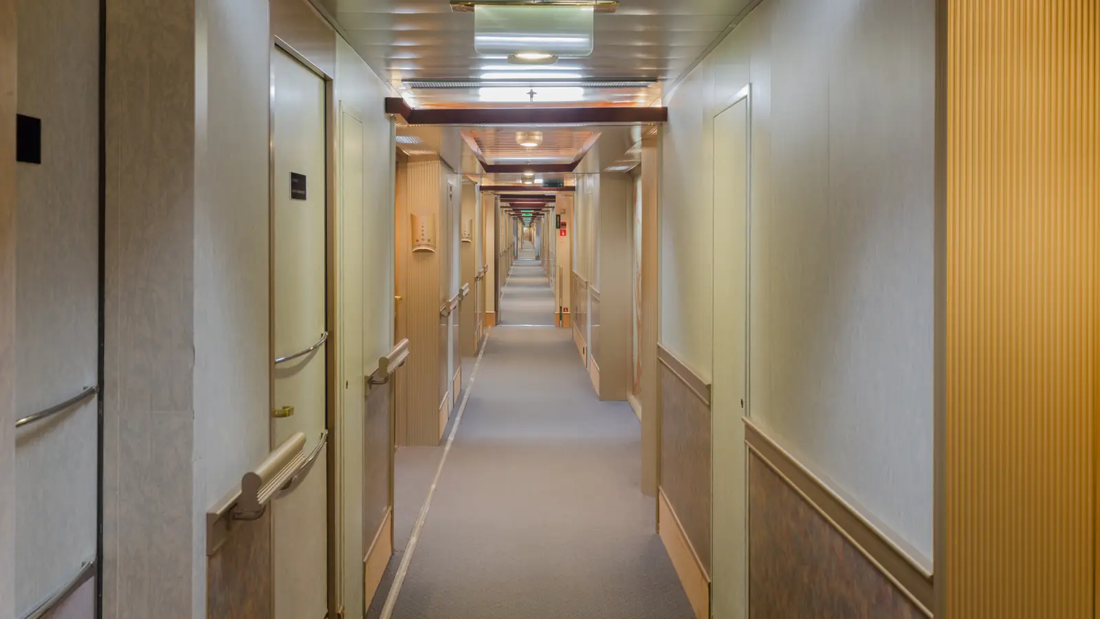 A long, empty cruise ship stateroom corridor lined with cabin doors