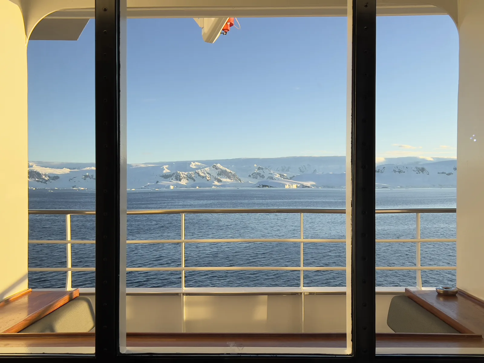 View of the sea and distant icy coastline through a cruise cabin balcony door