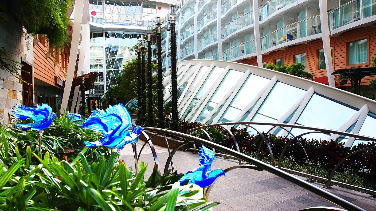 Tropical plants, glass bird sculptures and balconies in the open-air Central Park on Allure of the Seas